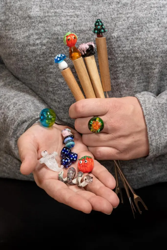 Beadmaker’s Bench Künstler-12von12 im November 2022: Das Glasperlenspiel. Hier werden verschiedenartige Ergebnisse gezeigt, darunter Schmuckstücke und niedliche Figuren aus Glas.