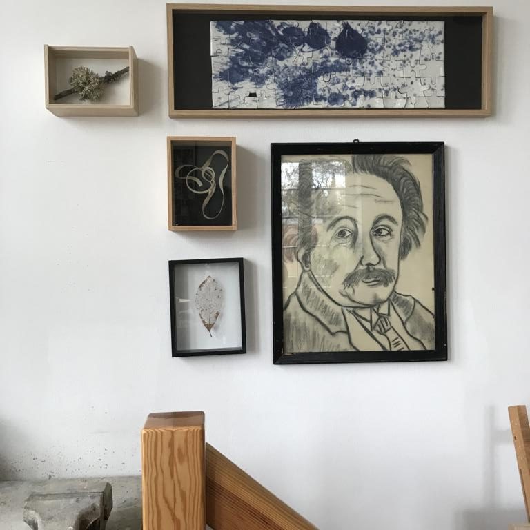 Über der Treppe bei Sommerkeramik hängen Bilder. Sie zeigen Einstein als Kohlezeichnung, ein Moos am Ast hinter Glas und ein Blatt, dem nur noch die Äderchen übriggeblieben sind.