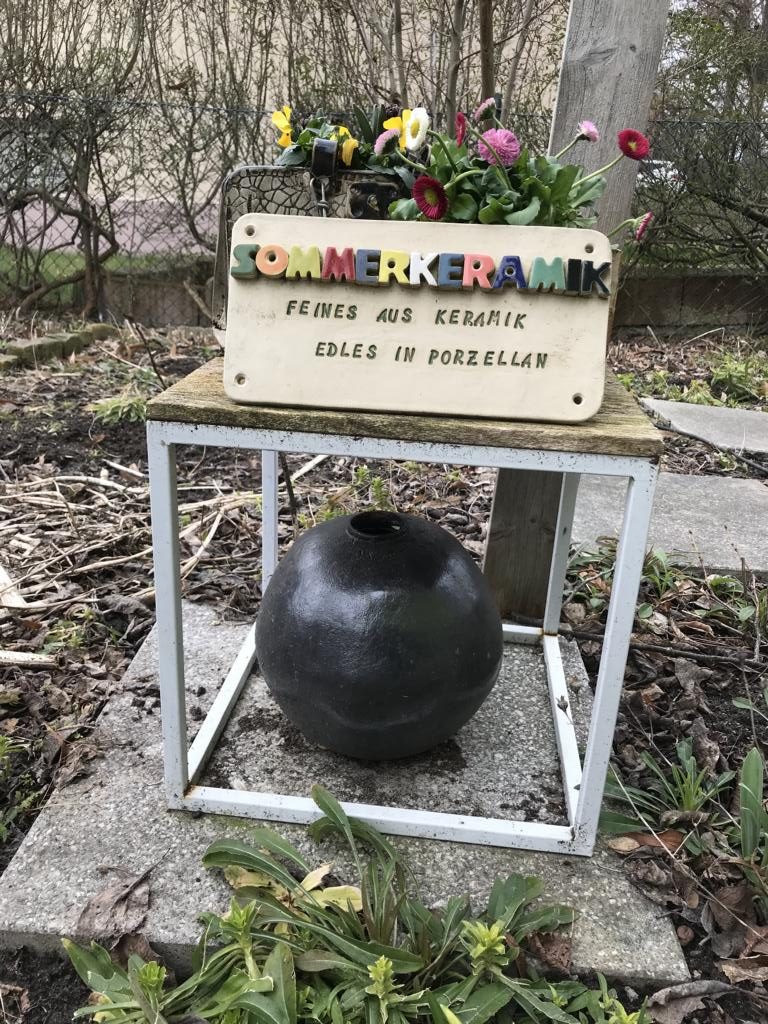 In bunten keramischen Lettern steht auf dem Schild: Sommerkeramik und darunter eingebrannt: Feines aus Keramik, Edles aus Porzellan. Das ist die Einladung dazu, die Töpferei besuchen kommen.