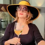 Auch Marina Trilk ist bei Old Petrocelli eingekehrt. Ihr Farbwahl liegt bei schwarz mit sonnigem Gelb als Hutkrempe und als Hutband. Folgerichtig trinkt sie ein Glas Wein, das sie in die Kamera hält, ohne sich darüber bewusst zu sein. Sie guckt ein bisschen abwesend durch ihre Sonnenbrille ins Nichts.