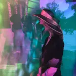 Marina Trilk durch Prisma fotografiert. Sie besticht durch ihren eleganten Hut mit gelber Krempe.