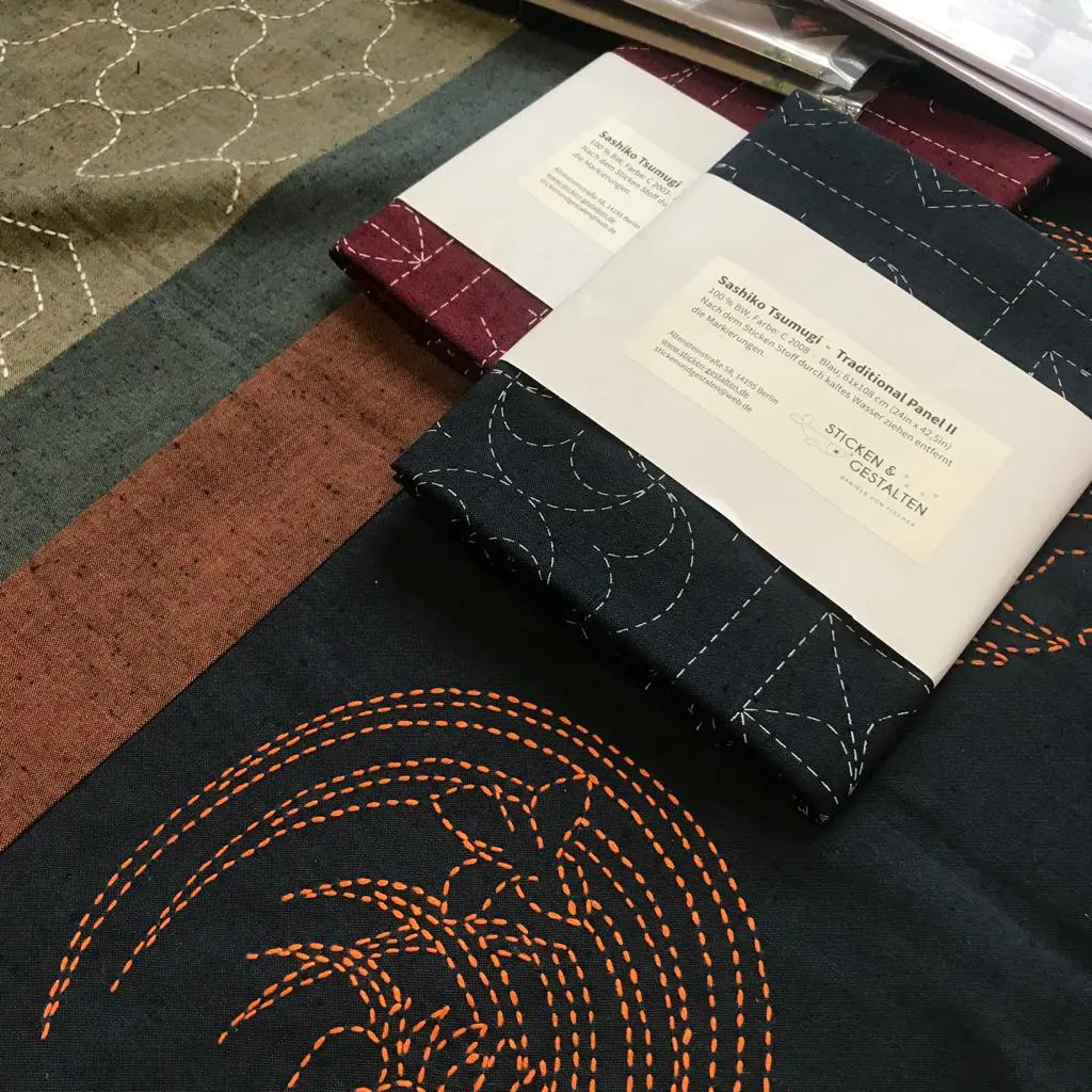 Daniele von Fischer hat Stickvorlagen bereitgelegt. Workshop-Teilnehmer beginnen ihre Arbeit und folgen ihren Anweisungen.