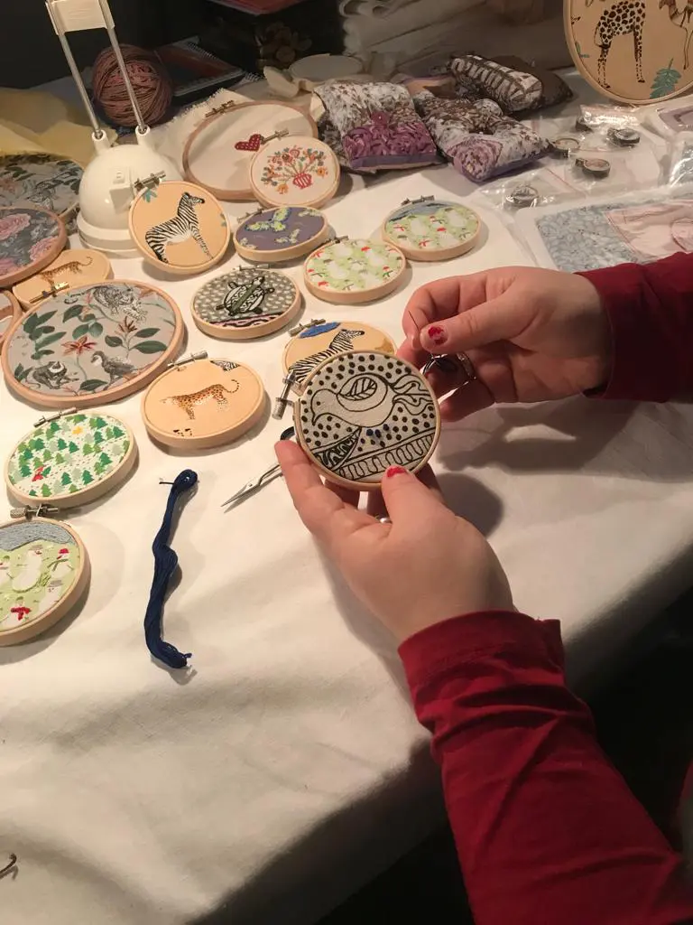 Margit Marschalls Workshopteilnehmerin stickt ein Huhn im kleinen Rahmen nach.