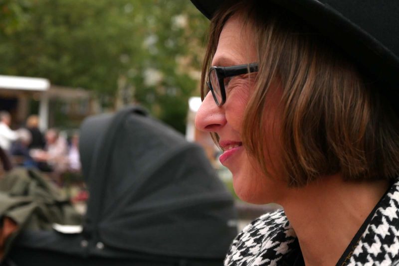 Arbeite mit mir: Sichtbarkeit und Umsatz? Ich weiß, wie es geht! Das bin ich, Claudia Scholz von der Seite fotografiert. Beim Weinbrunnen sitzt sie mit anderen bei der Vorbereitung für den Moving Table beim Wein- und Winzerfest Lichtenrade
