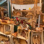 Marktstand mit handgefertigten Holzobjekten wie Schalen, Kerzenhaltern und Skulpturen, dekoriert mit roten Kerzen und Naturmaterialien