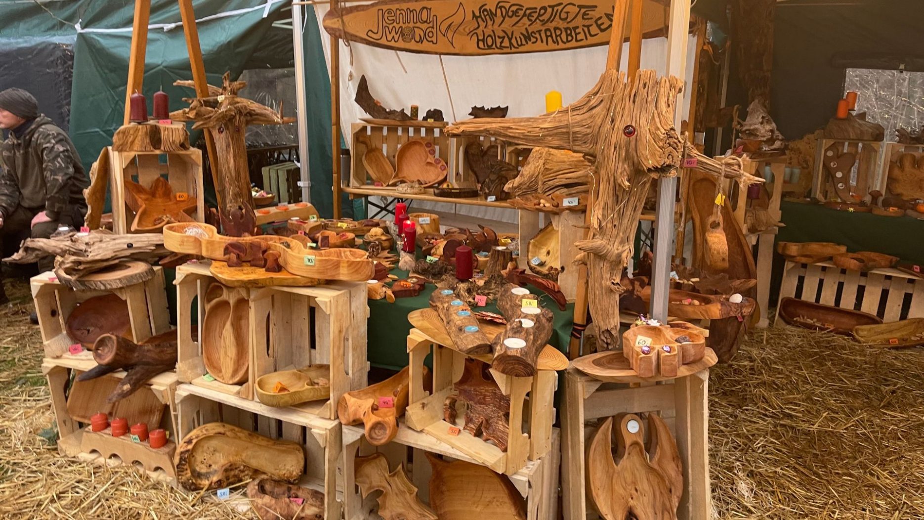 Marktstand mit handgefertigten Holzobjekten wie Schalen, Kerzenhaltern und Skulpturen, dekoriert mit roten Kerzen und Naturmaterialien