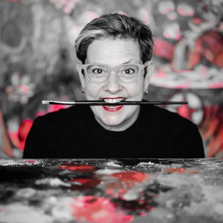 Die 12von12 von Nadja Schüller-Ost behandelt die Malerin, die sich selbst als Kunstrebellin aus Berlin bezeichnet. Sie malt gern mit leuchtendem Rot, das an frisches Blut erinnert. Den Pinsel quer im Mund schaut sie angriffslustig in die Kamera. Das Bild ist in schwarz-weiß gehalten mit eben jenem leuchtenden Rot.