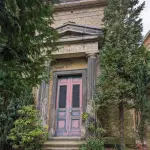 Der Eingang zu einem vergessenen Totenhaus mit rosa-gestrichenen Tür mit blauer Einfassung