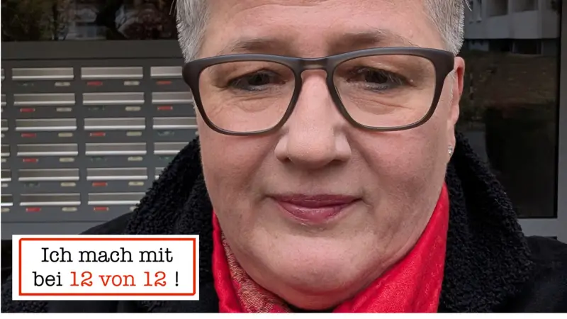 Birgit Helmlingers 12von12 im März 2025: Fotografie mit Durchblick - mit rotem Schal, Brille und konzentriertem Blick vor dem Klingelschild eines Wohnhauses in Berlin
