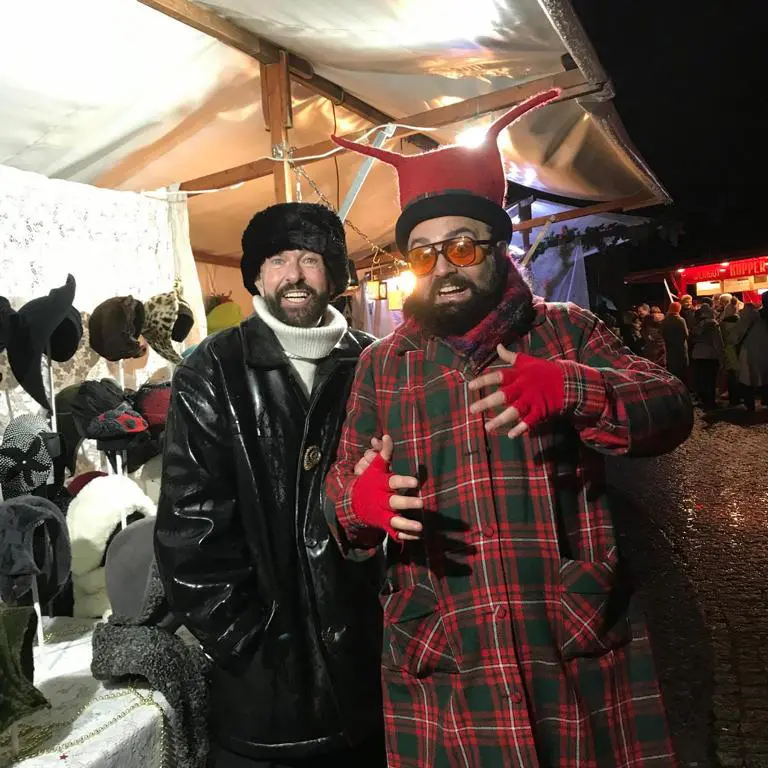 Carlos als ernster Bruder des Winters und Gianni als Weihnachtskobold vor dem Hutstand auf dem WEINachtsmarkt 2024.
