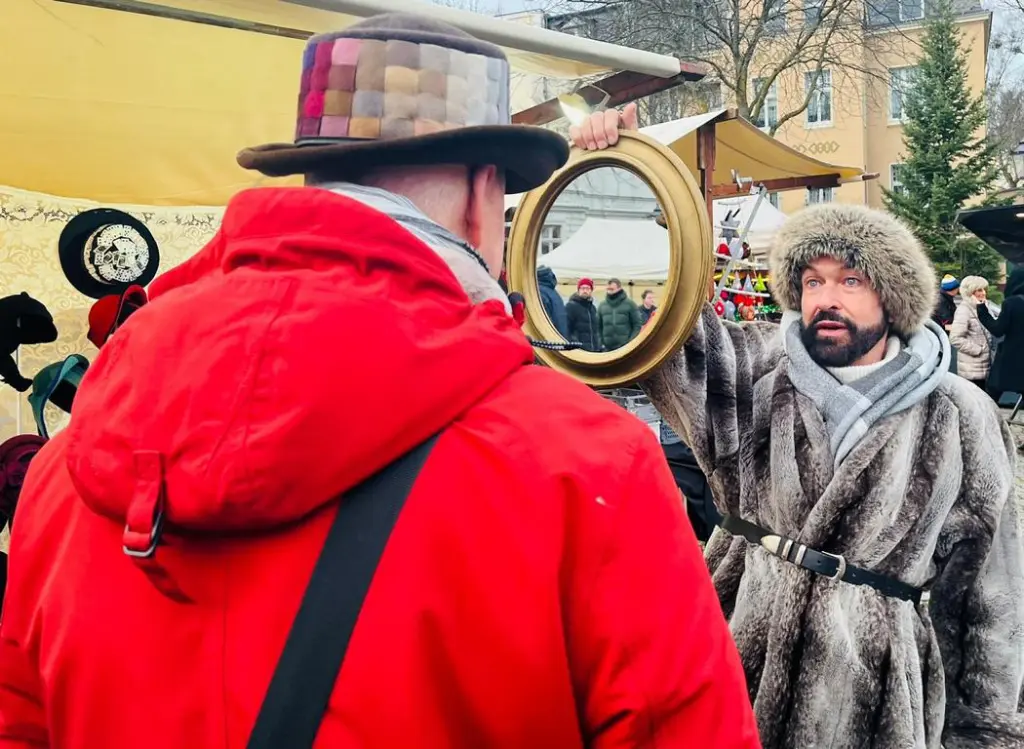 Carlos hält einem Kunden den Spiegel entgegen – beim WEInachtsmarkt am Ludwig-Beck-Platz 2025, ein Moment vor der Entscheidung.